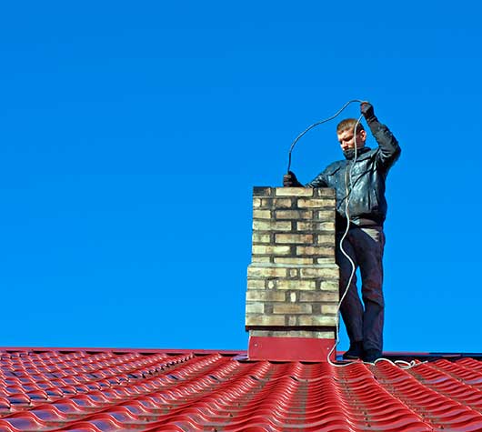 Man Cleaning Chimney with Metal Brush on Long Cable